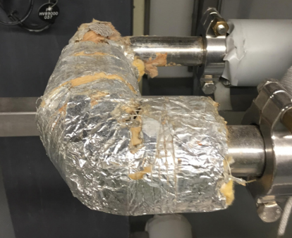 Damaged stone wool HVAC insulation on pipe elbow.