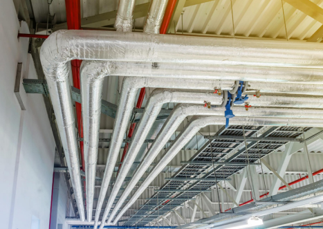Foil-faced stone wool insulation on overhead HVAC pipes.